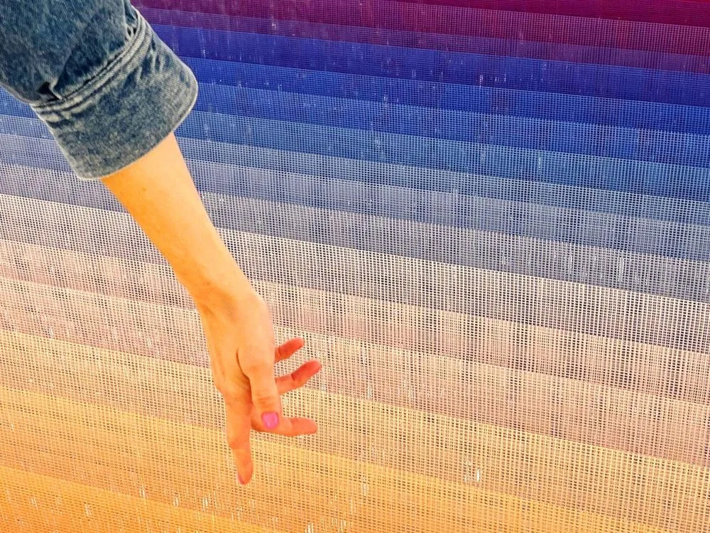 A visitor reaching toward a thread installation