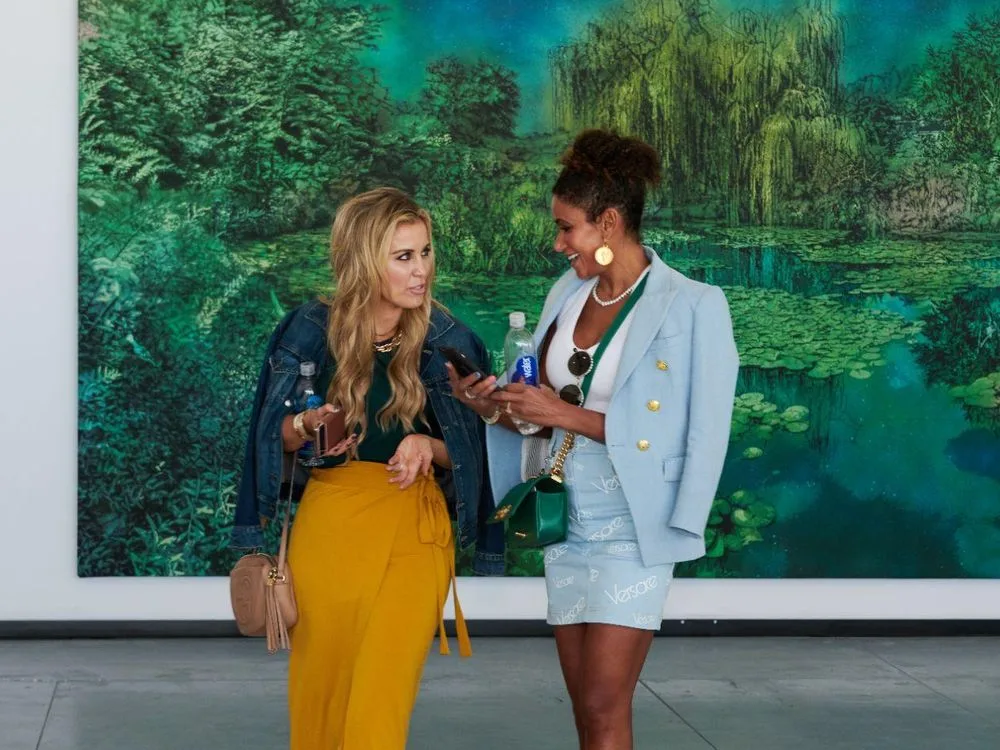 Two visitors talking in front of a large landscape painting