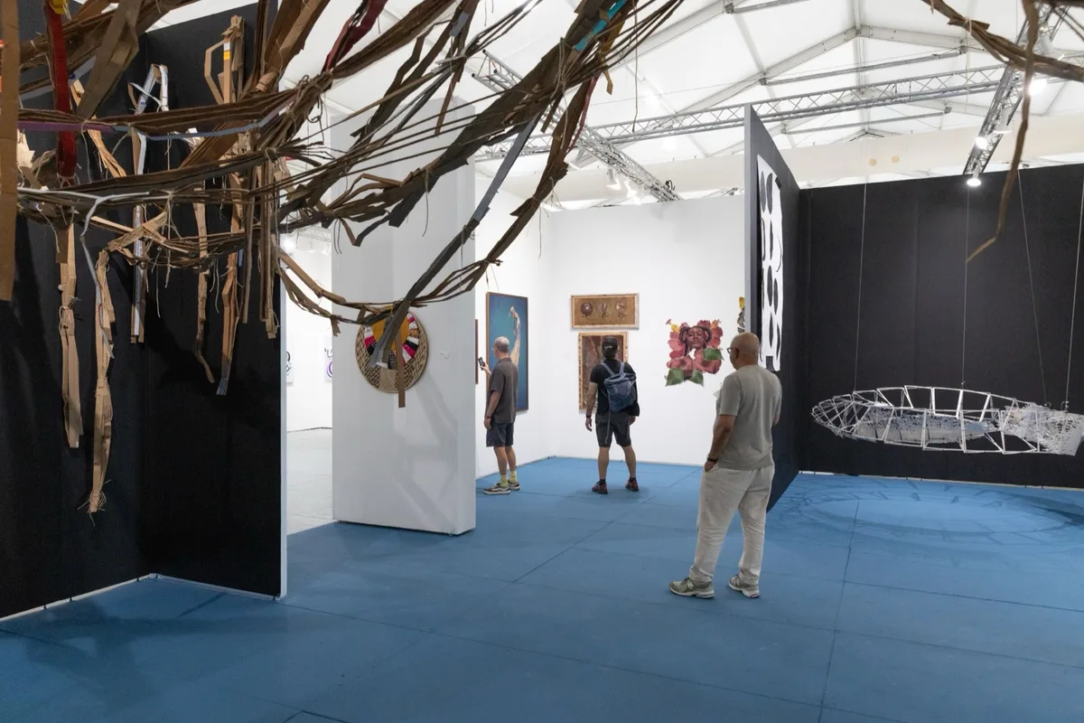 Visitors walk across a blue floor between gallery booths